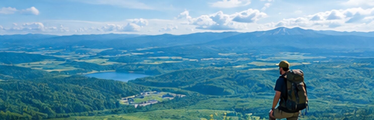 Green summer mountain landscape in Hokkaido, with a lake and farmland below